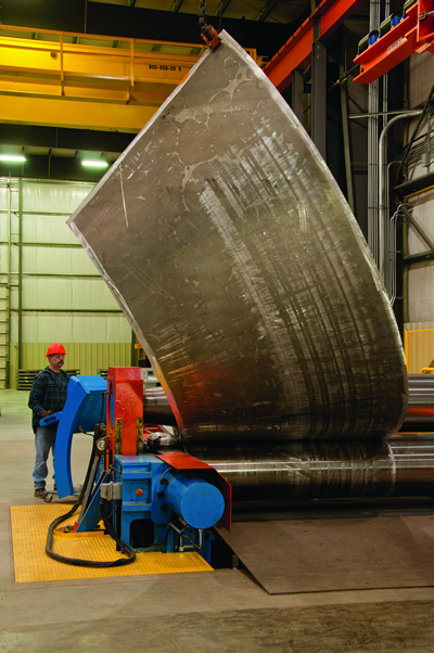 Worker operating a rolling and forming machine to create an aluminum cone at a Greiner facility