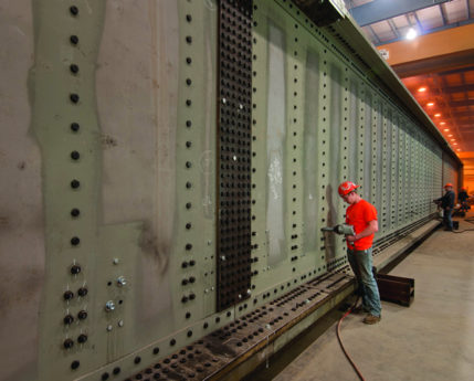 Worker riveting a railroad bridge in a Greiner facility