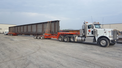 A specialized oversize transit trailer hauling a steel beam